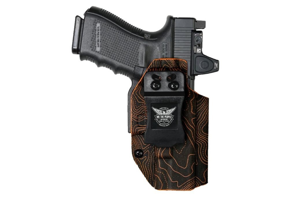 A black handgun in a tactical holster featuring an orange and black topographic design, showing the grip and trigger guard. The holster includes an attachment for additional features.
